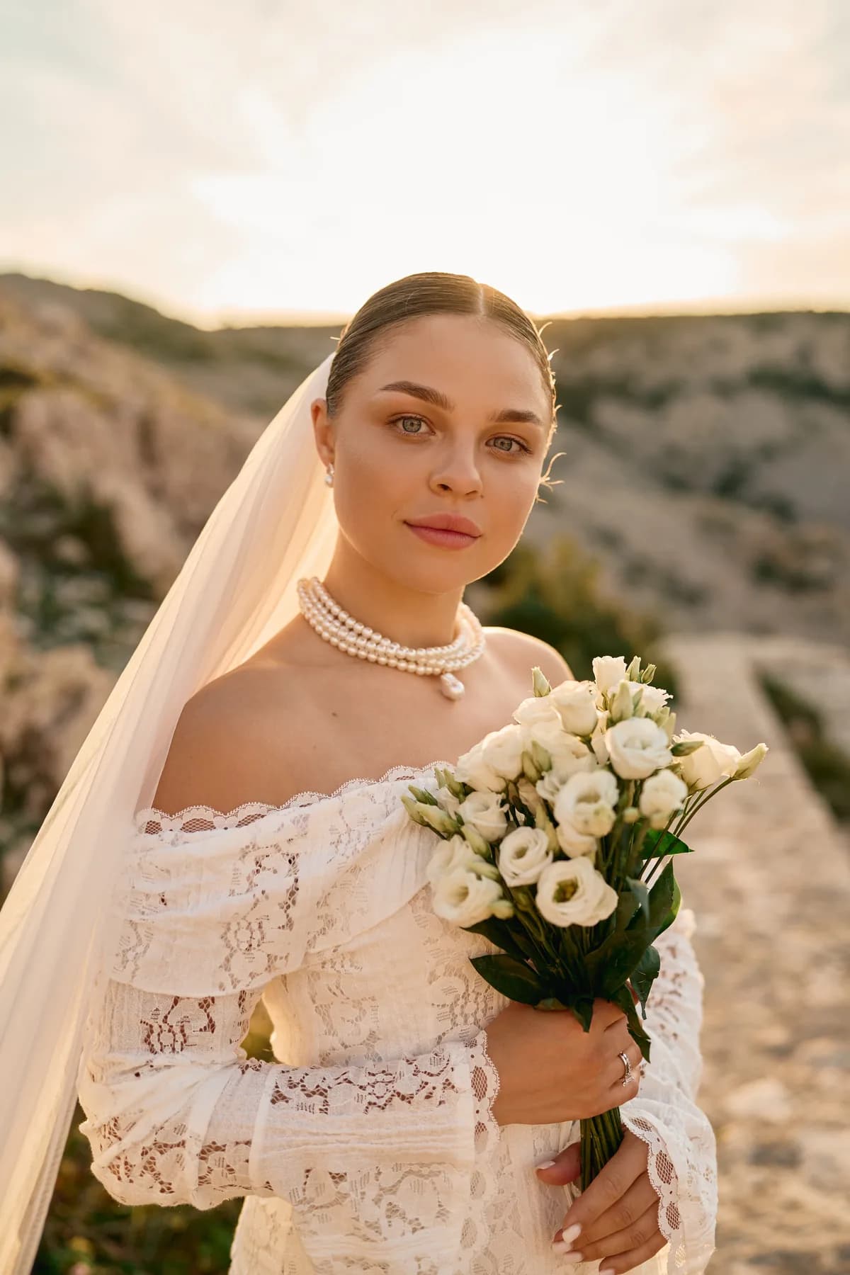 Bridal portrait with bouquet and lace veil in evening light