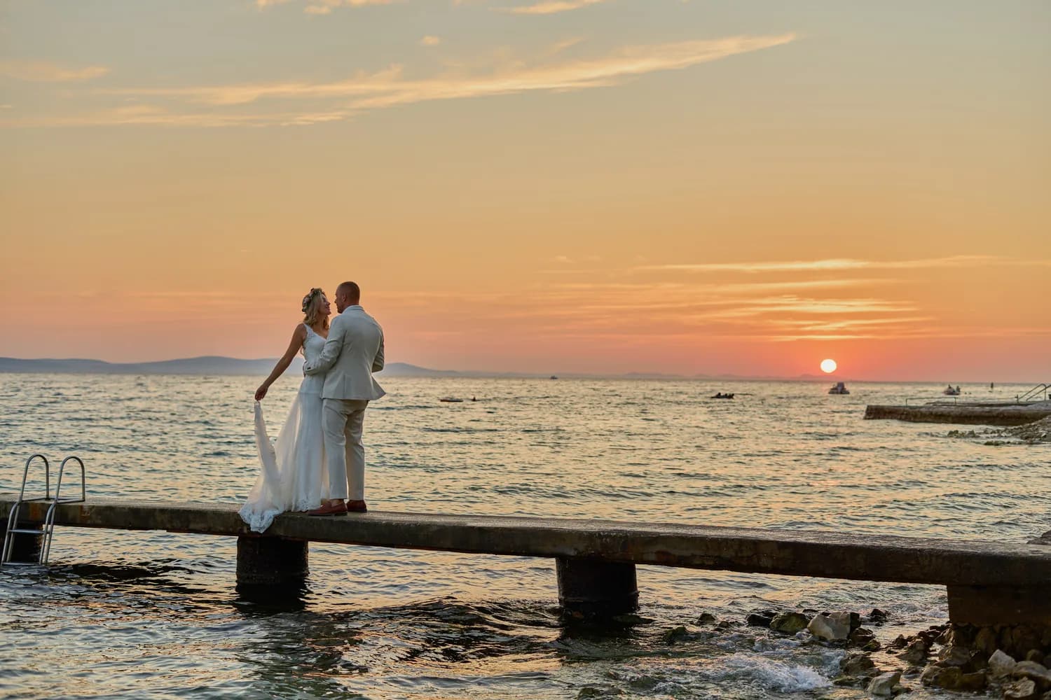 Couple on a jetty as the sun sets over the sea