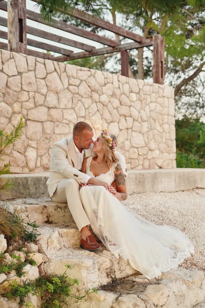 Groom kissing his bride's forehead on sunlit stone steps