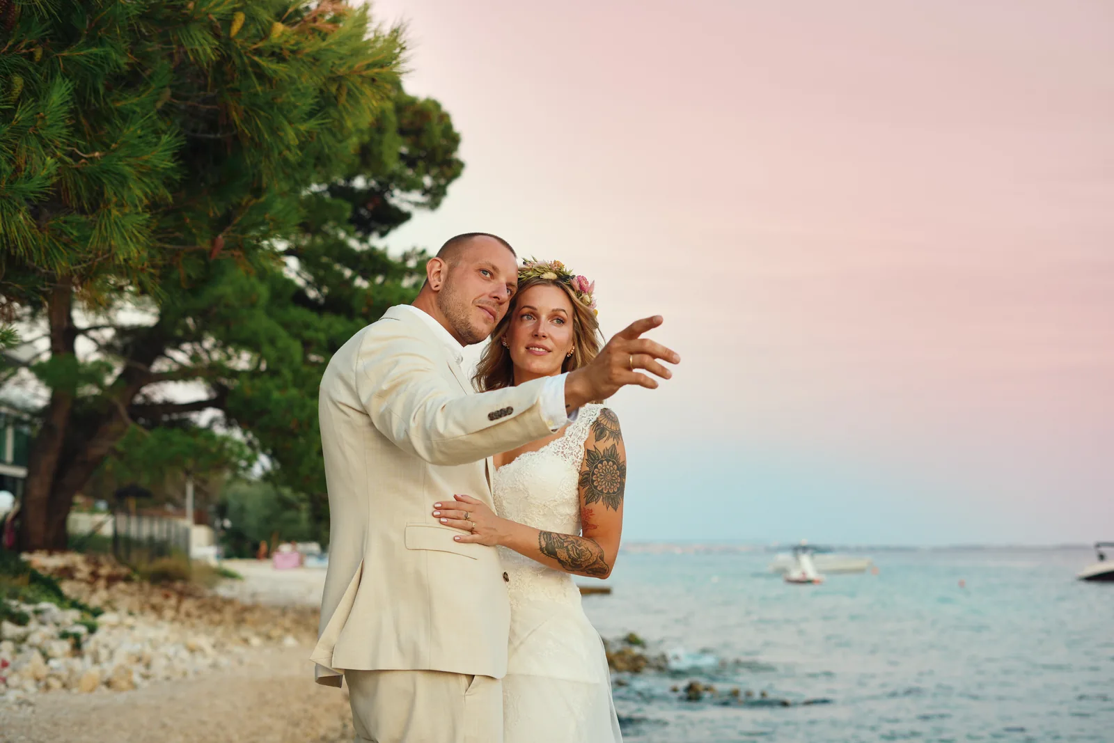 Couple by the sea under a soft pink sunset sky