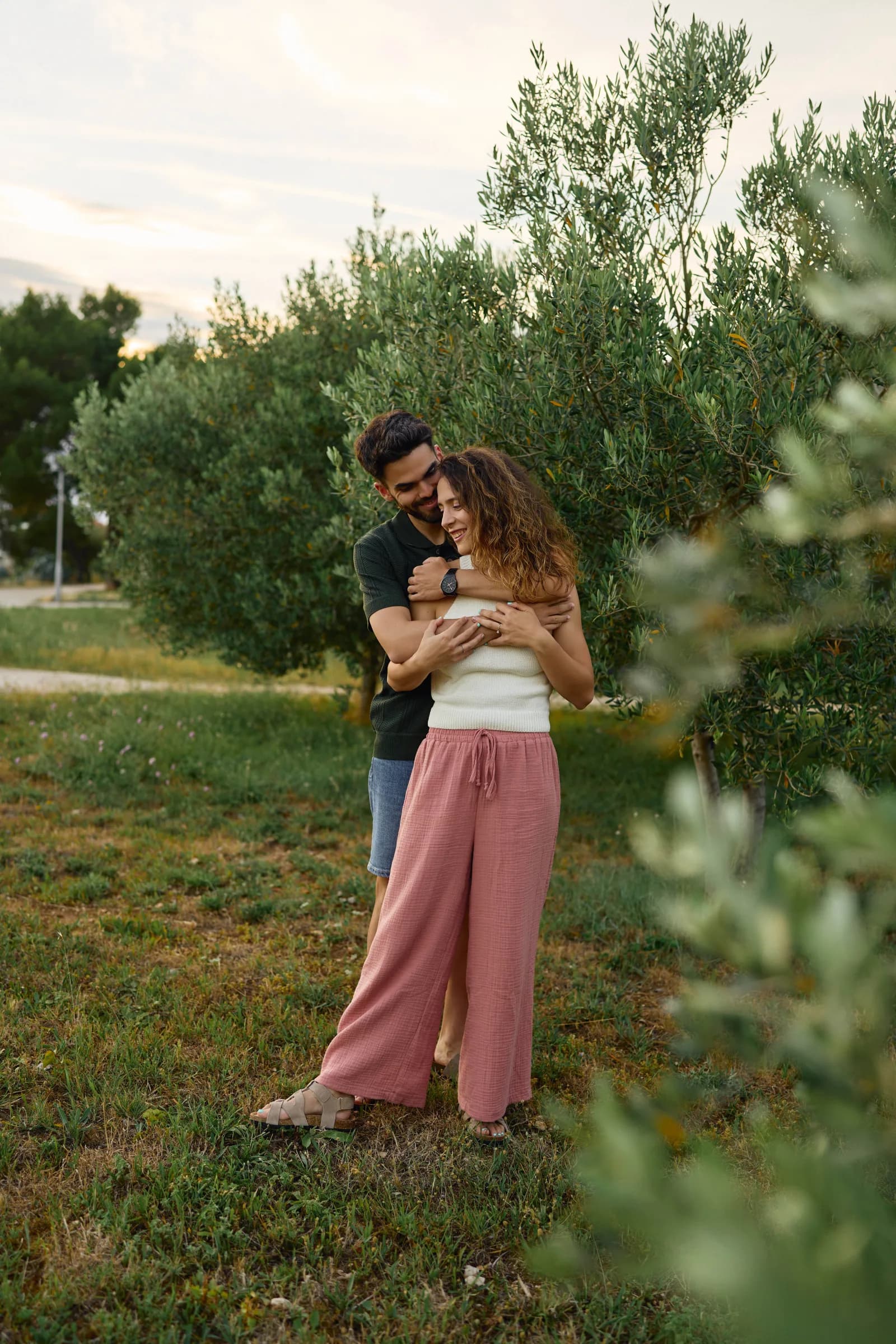 Couple embracing in an olive garden at golden hour