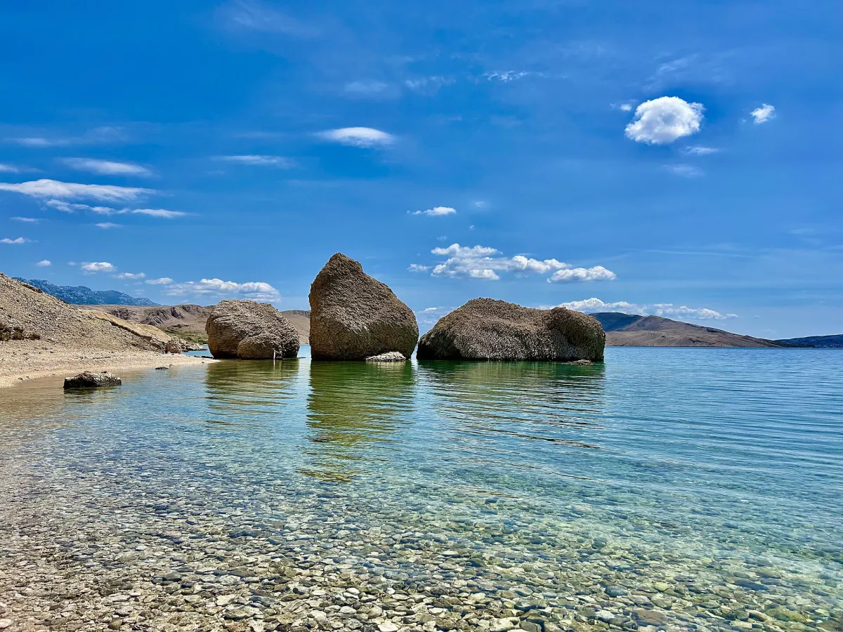 Large boulders standing in the clear shallow water at Beritnica beach near Metajna